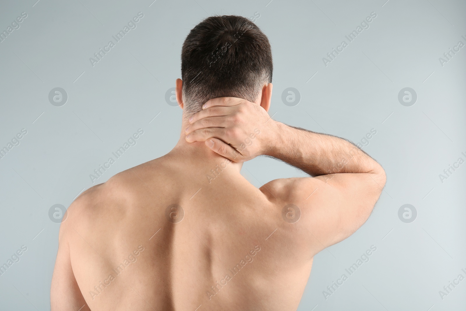 Photo of Young man suffering from neck pain on light background