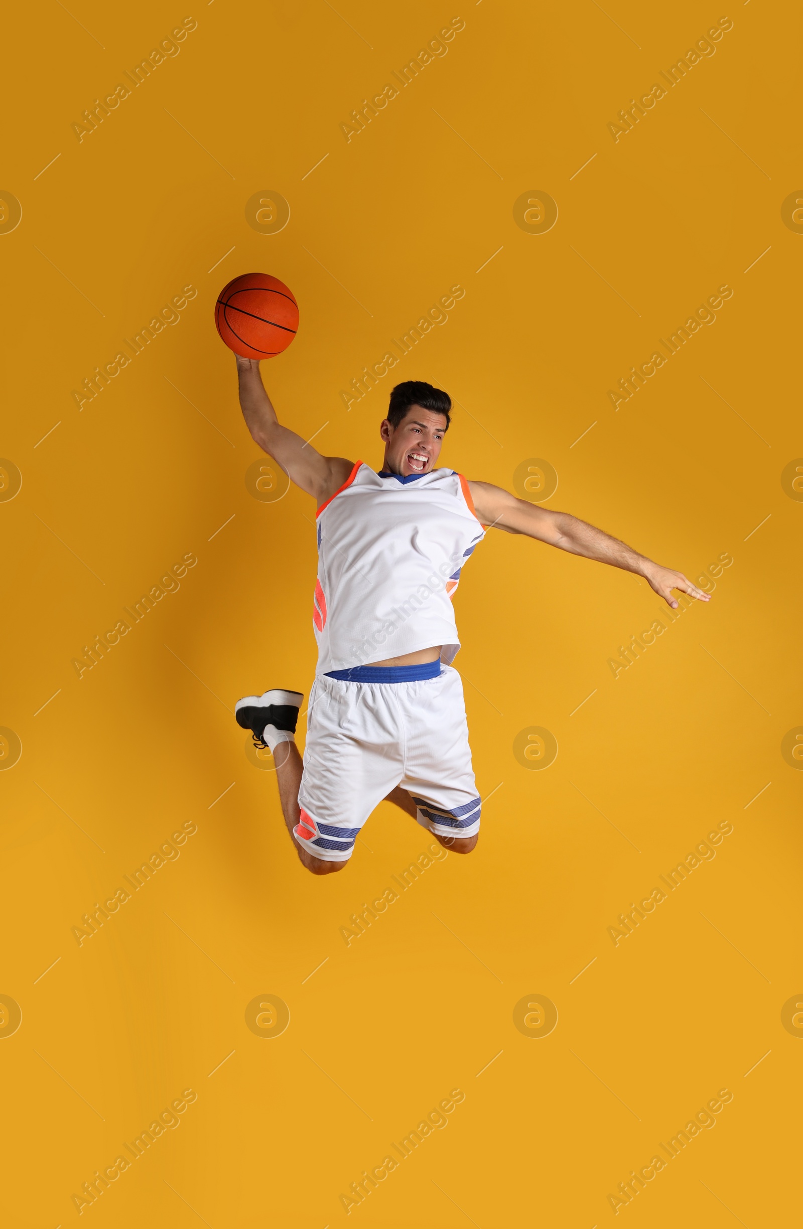 Photo of Professional sportsman playing basketball on yellow background