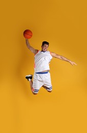 Photo of Professional sportsman playing basketball on yellow background