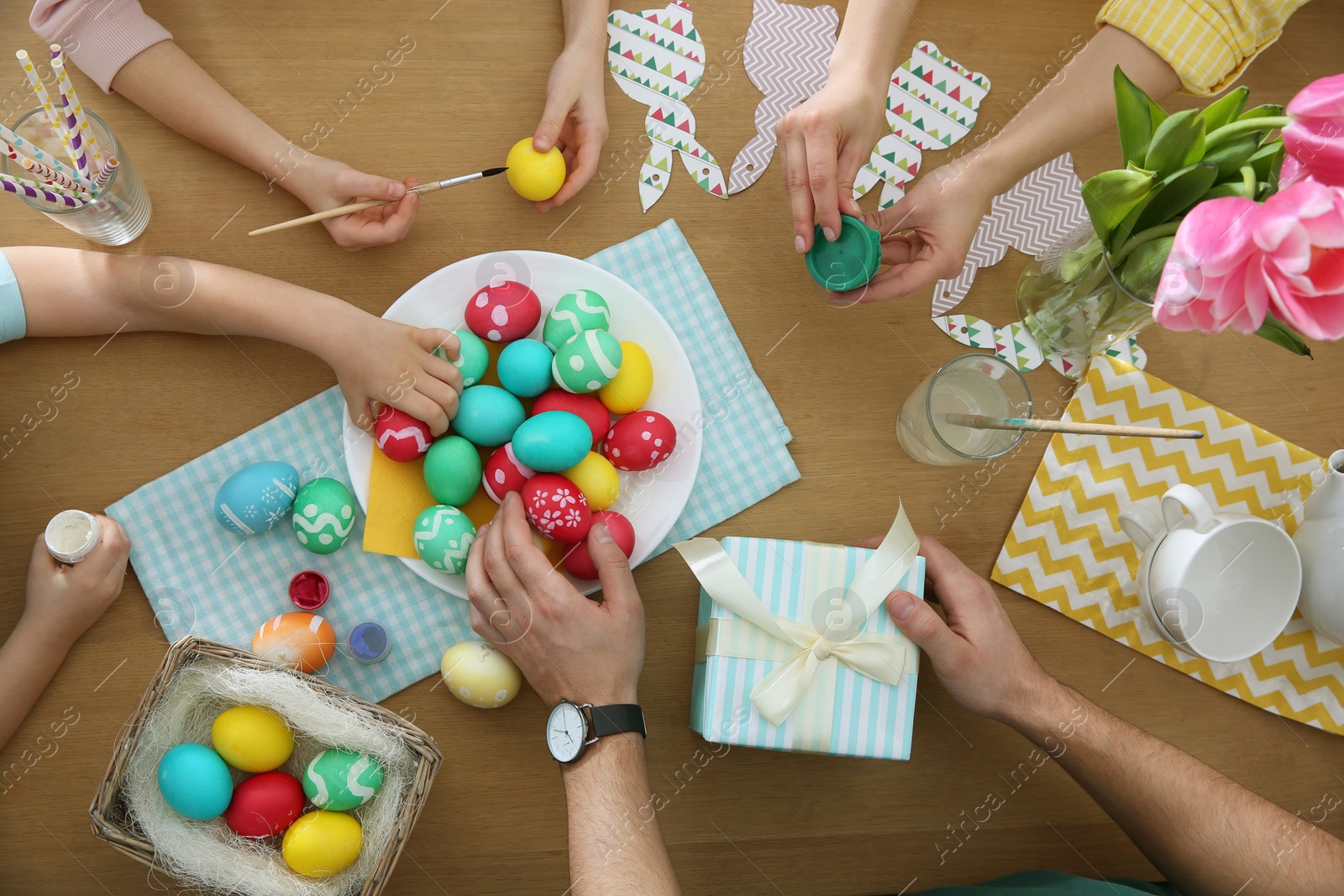 Photo of Family with colorful Easter eggs at table, top view
