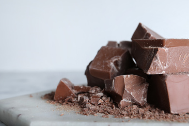 Pieces of tasty milk chocolate on board, closeup