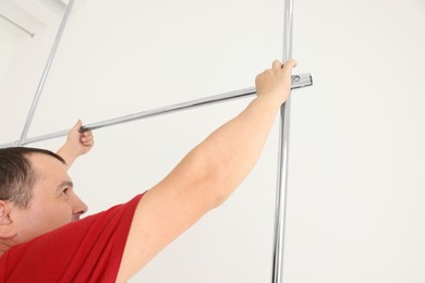 Worker installing new metal pipes indoors near white wall