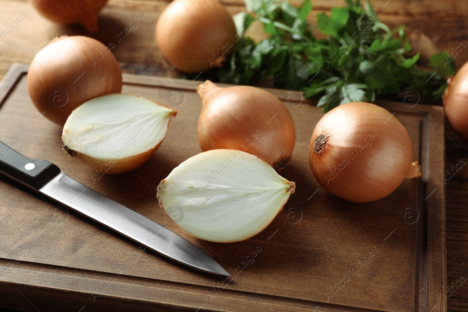 Photo of Whole and cut onions on wooden table