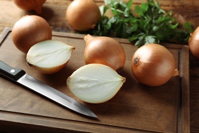 Whole and cut onions on wooden table