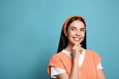 Photo of Young woman wearing stylish bandana on light blue background, space for text