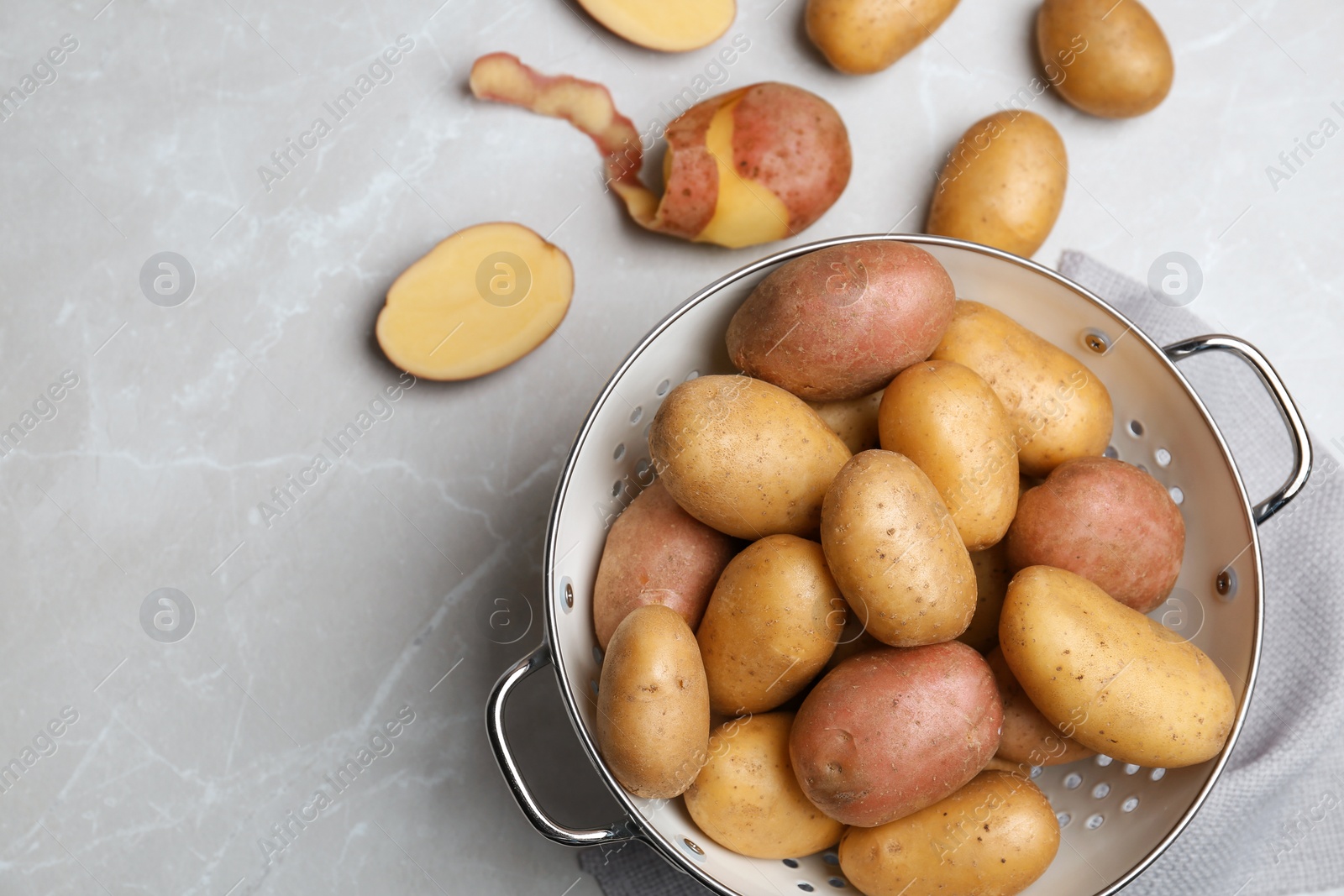 Photo of Colander with fresh ripe organic potatoes on grey background, top view