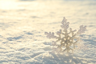 Photo of Beautiful decorative snowflake in white snow, outdoors. Space for text