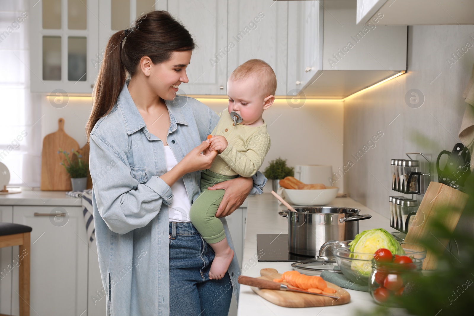 Photo of Happy young woman and her cute little baby cooking together in kitchen