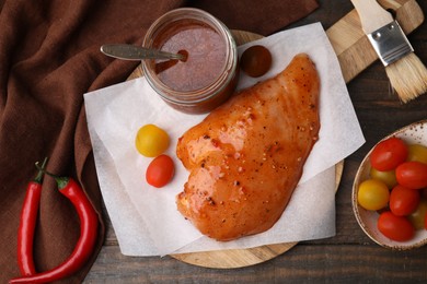 Photo of Fresh marinade and raw chicken fillets on wooden table, flat lay