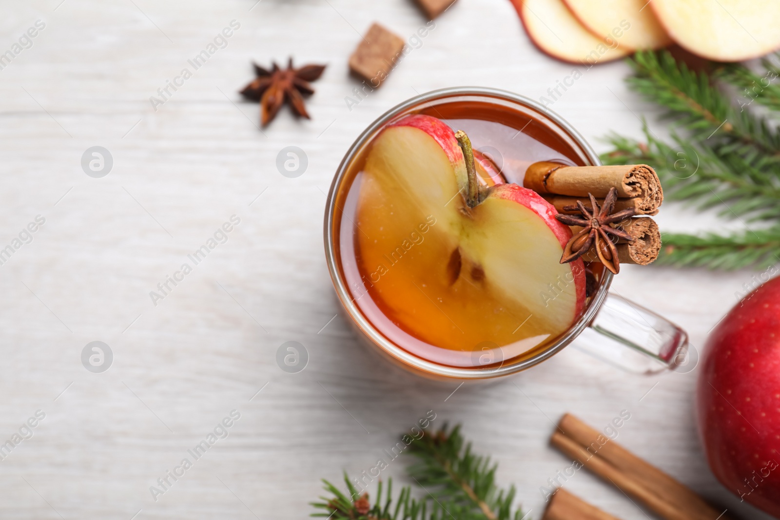 Photo of Hot mulled cider, ingredients and fir branches on white wooden table, flat lay. Space for text