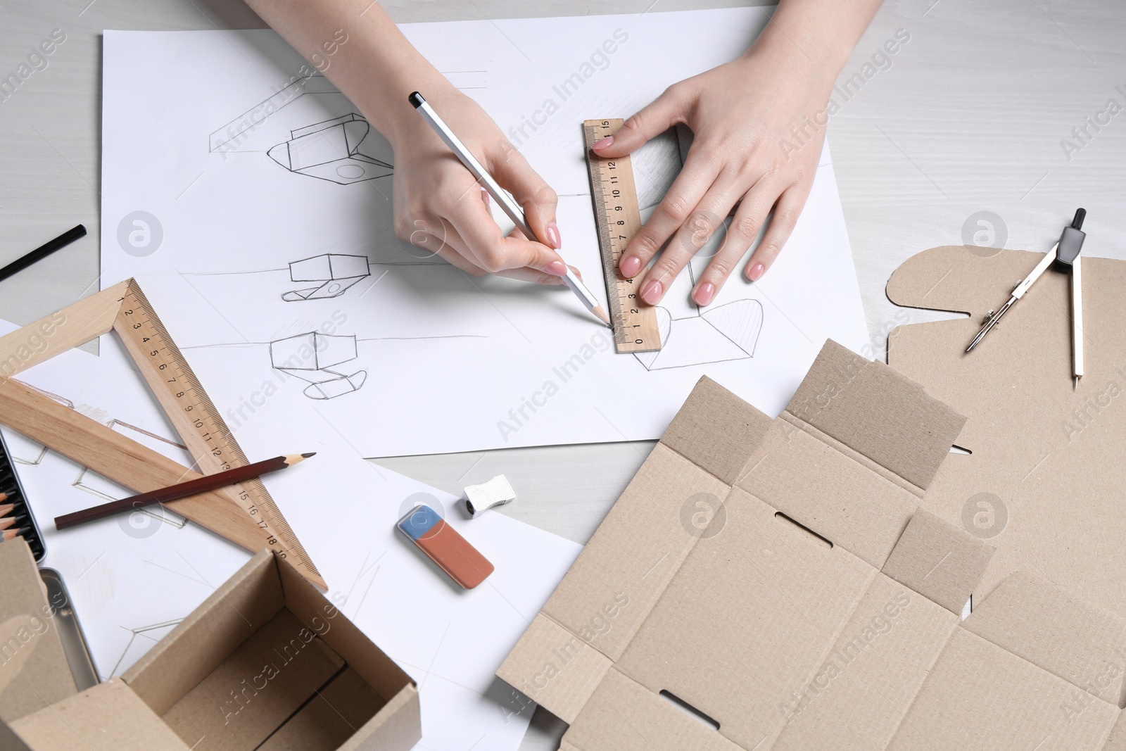 Photo of Woman creating packaging design at light wooden table, above view