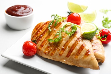 Photo of Tasty grilled chicken fillets with cherry tomatoes, lime slice and arugula on light table, closeup