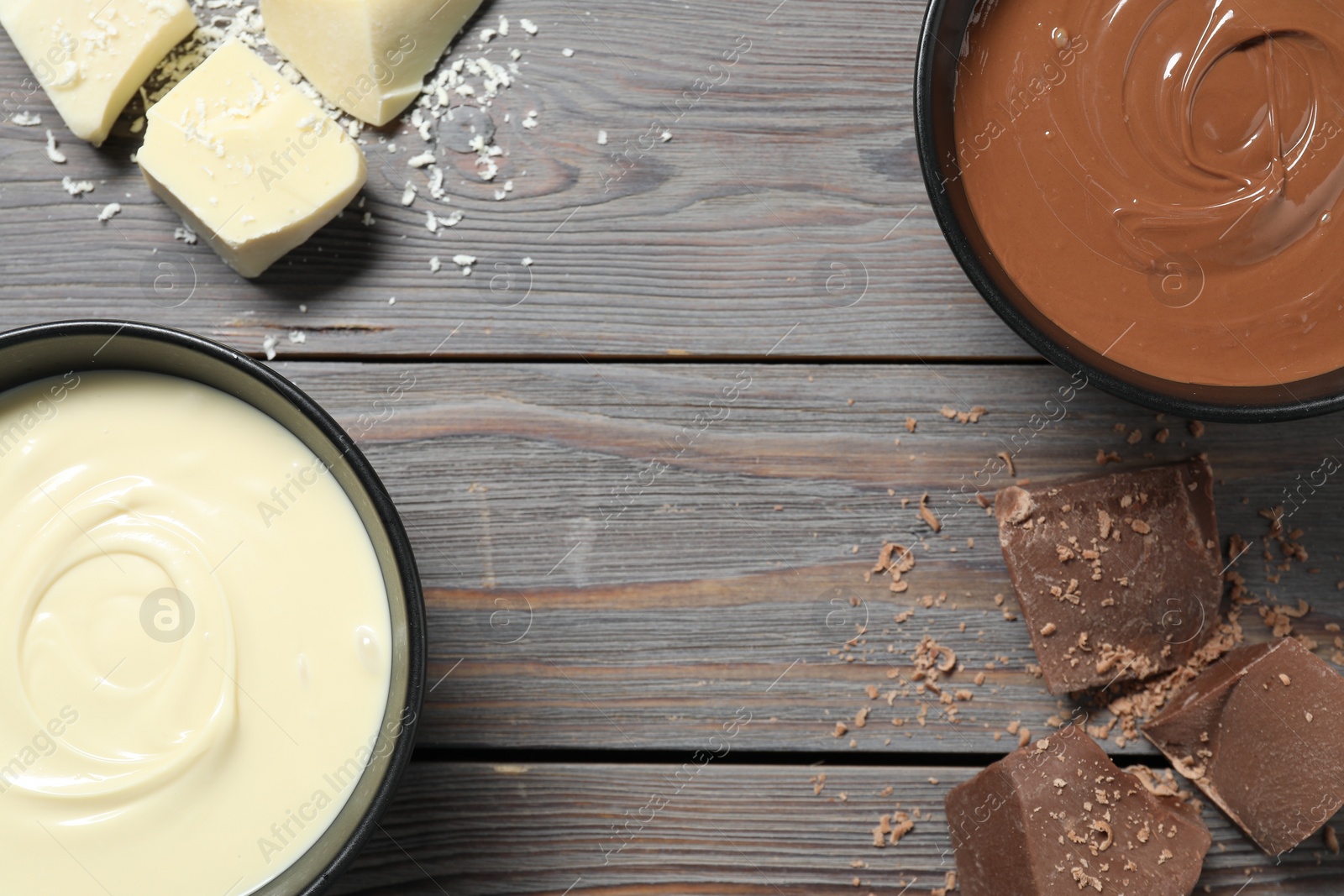 Photo of Tasty chocolate paste in bowls and pieces on wooden table, top view. Space for text