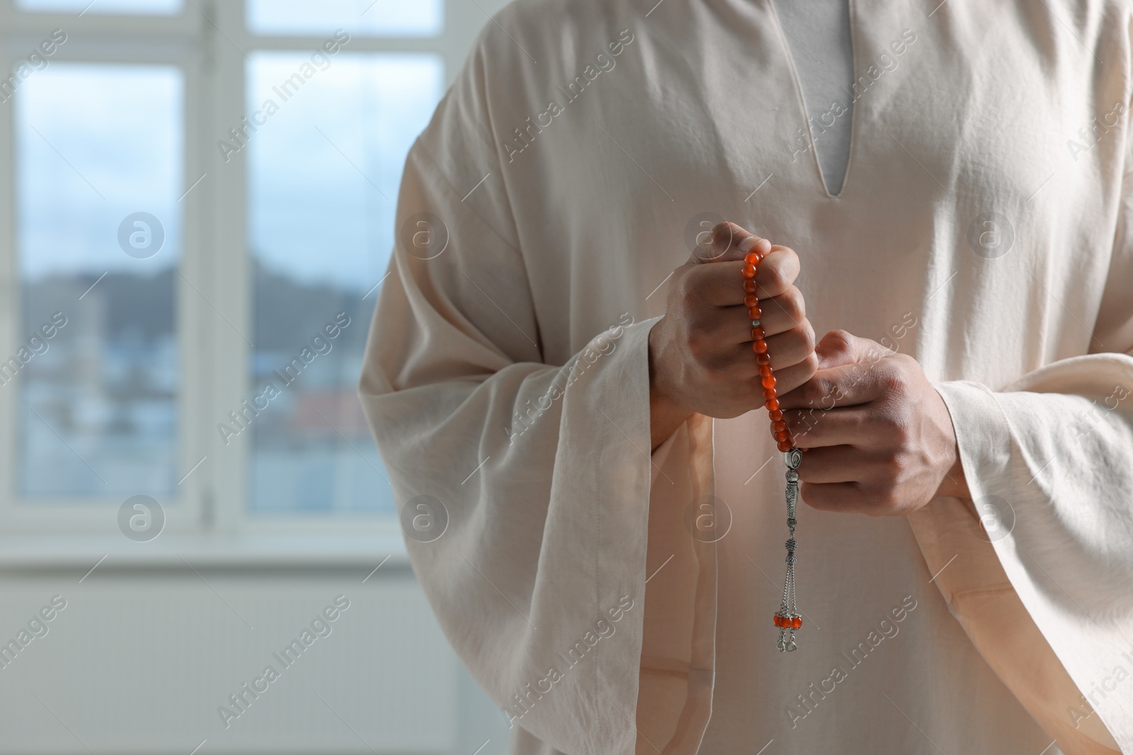 Photo of Muslim man with misbaha indoors, closeup. Space for text