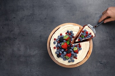 Photo of Woman taking piece of delicious homemade red velvet cake from table, top view