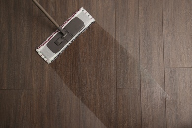 Photo of Cleaning of wooden floor with mop, top view. Space for text