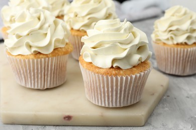 Photo of Tasty cupcakes with vanilla cream on grey table, closeup