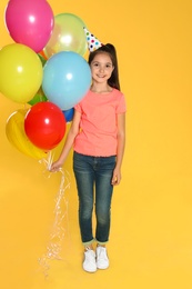 Photo of Happy girl with balloons on yellow background. Birthday celebration