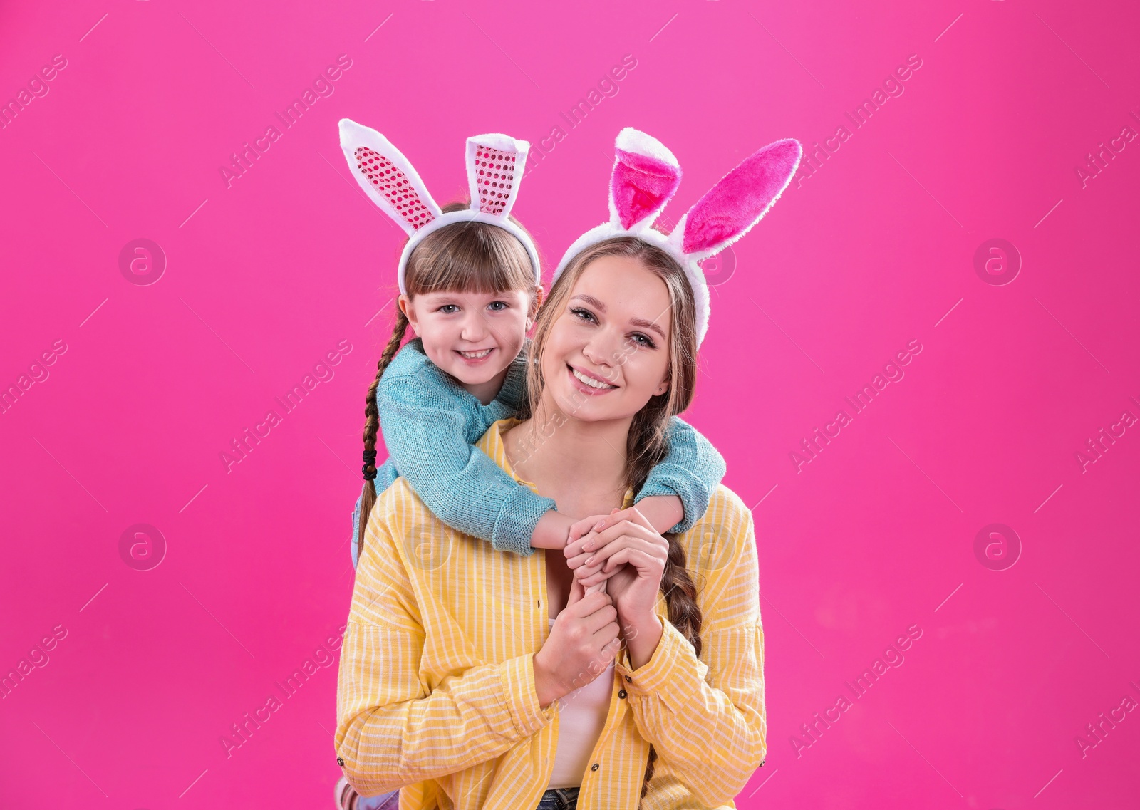 Photo of Happy woman and daughter with bunny ears on color background