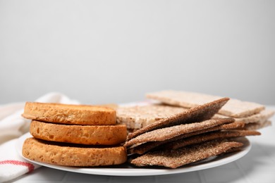 Photo of Platerye crispbreads, rice cakes and rusks on white table, space for text