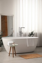 Photo of White tub and decor in light room. Interior design