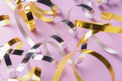 Photo of Shiny serpentine streamers on lilac background, closeup