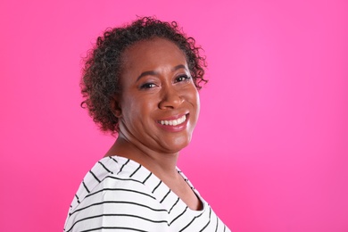 Portrait of happy African-American woman on pink background