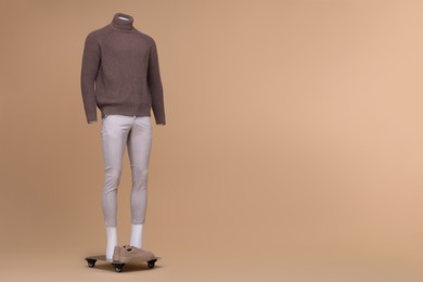 Photo of Male mannequin dressed in stylish turtleneck and pants on beige background. Space for text