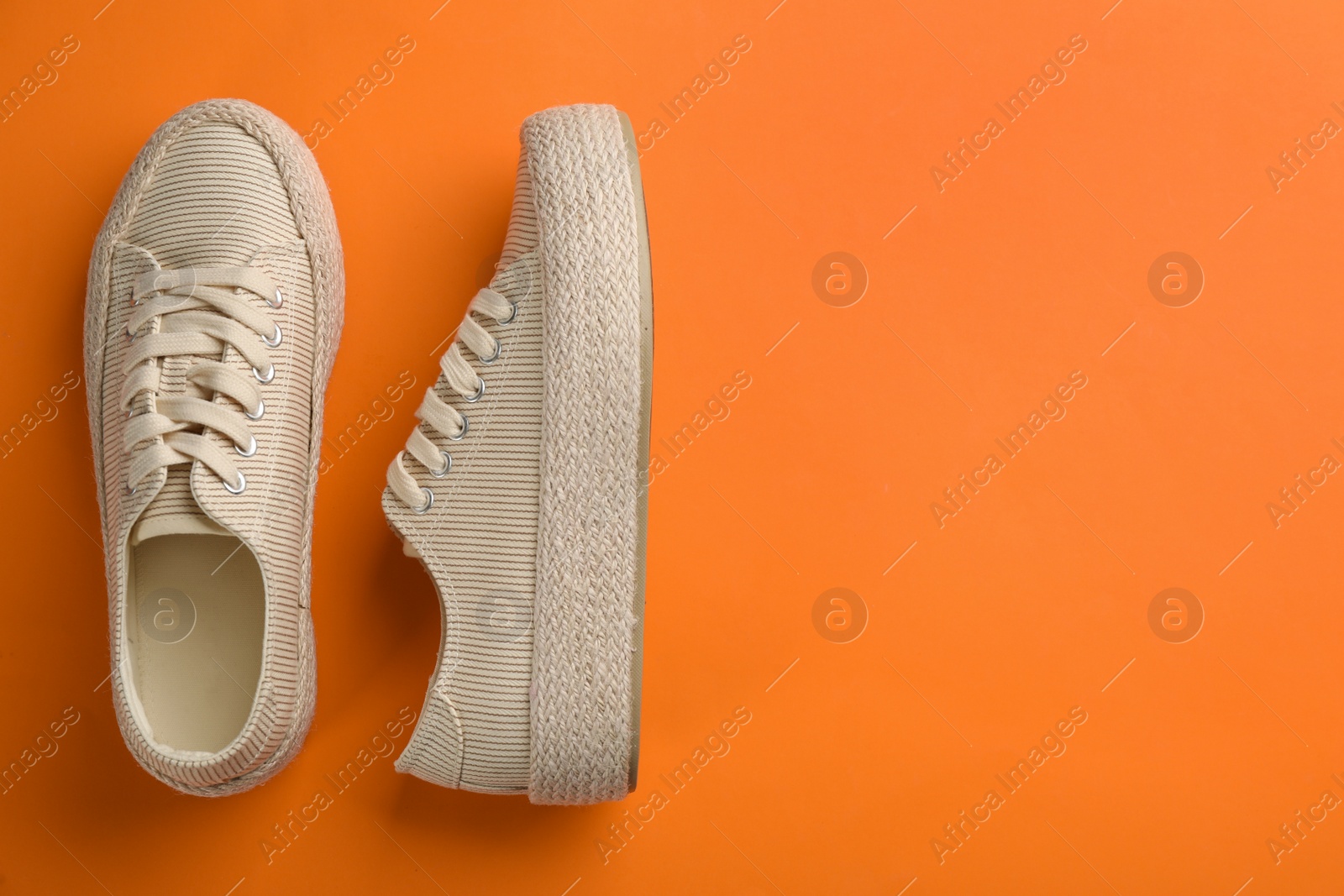 Photo of Pair of stylish comfortable shoes on orange background, flat lay. Space for text