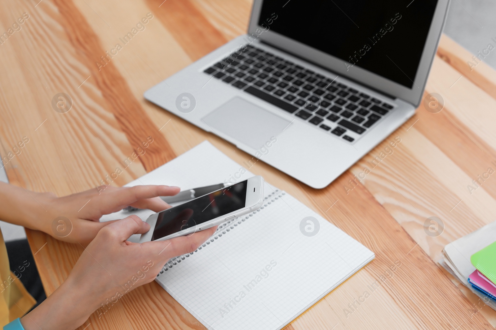 Photo of Young woman working with mobile phone and laptop at desk. Home office