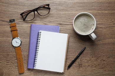 Photo of Flat lay composition with office stationery and cup of coffee on wooden table. Space for design