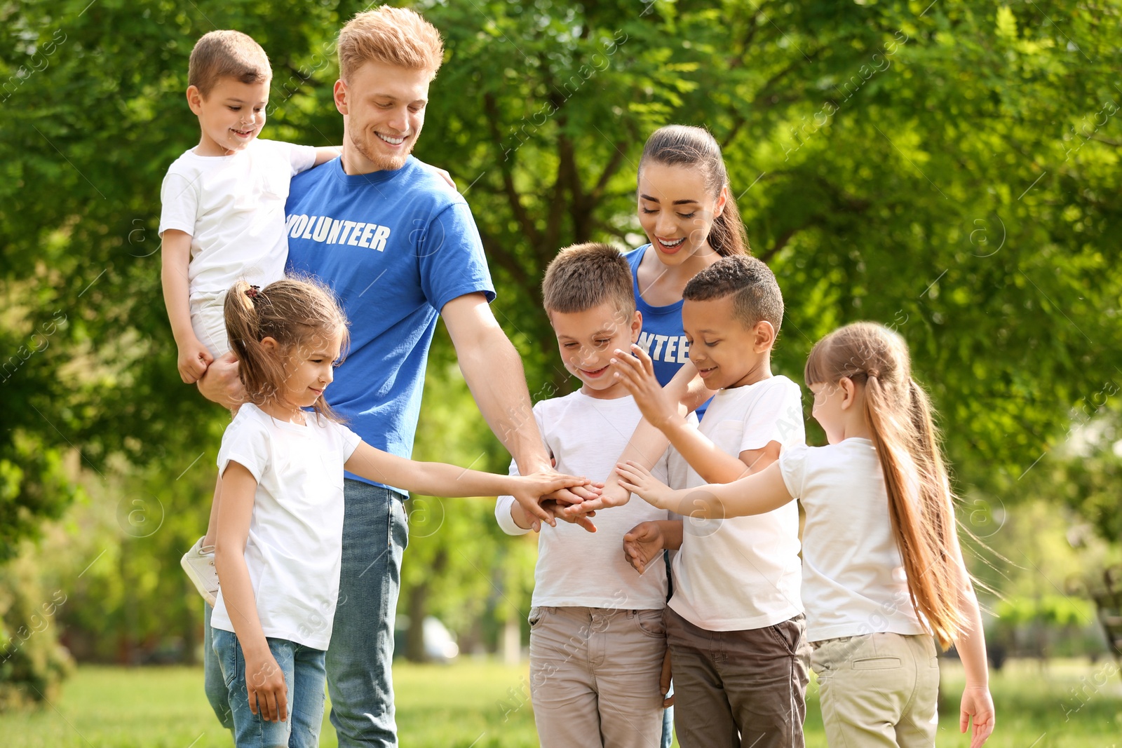 Photo of Group of kids joining hands with volunteers in park