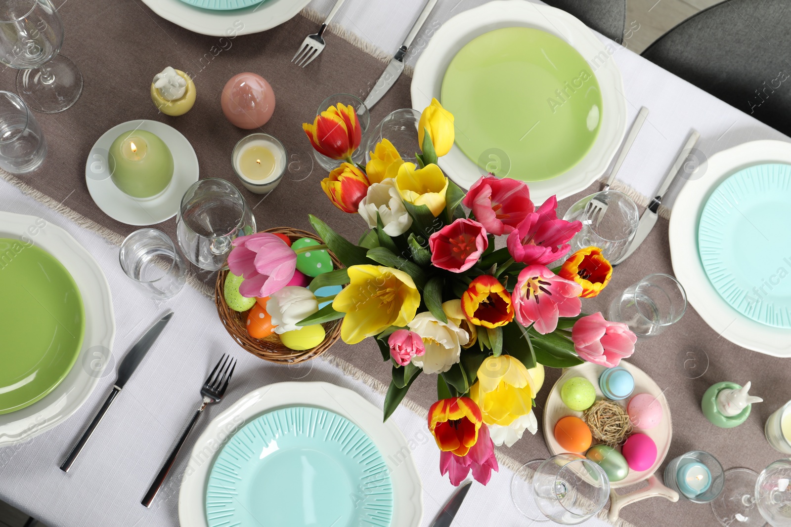 Photo of Easter celebration. Festive table setting with beautiful flowers and painted eggs, top view