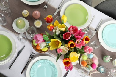 Easter celebration. Festive table setting with beautiful flowers and painted eggs, top view