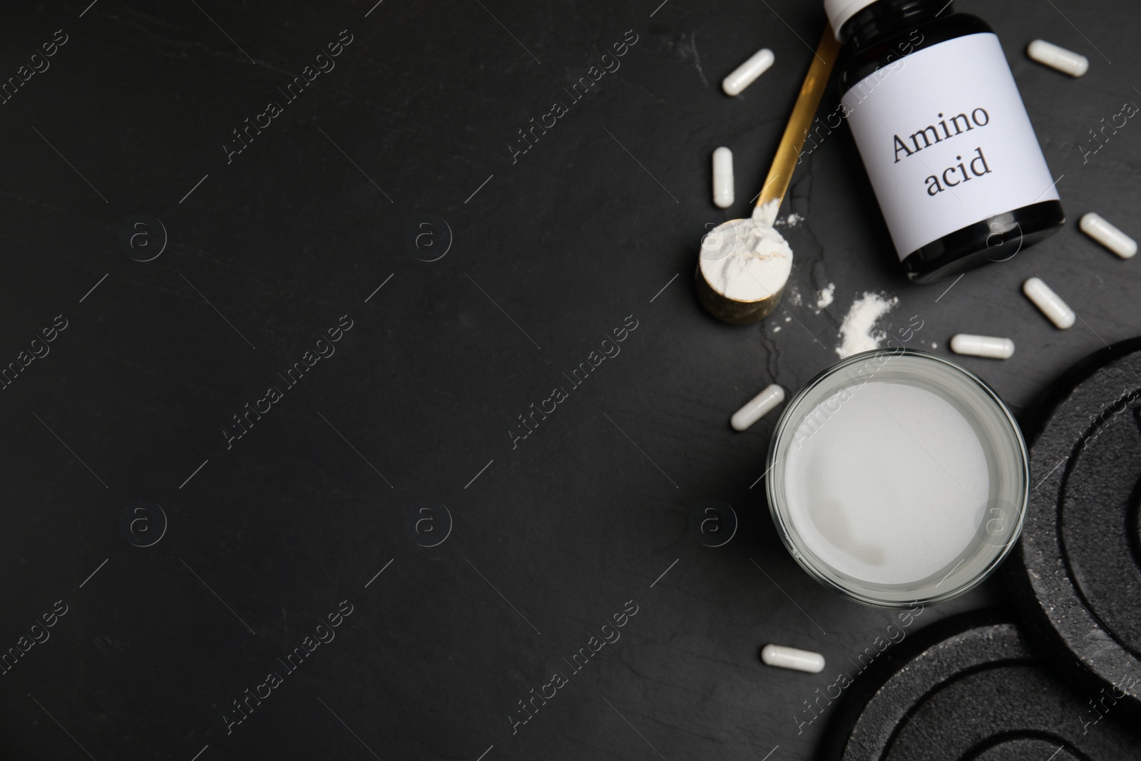 Photo of Amino acid shake, powder, pills and weight plates on black background, flat lay. Space for text