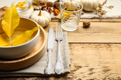 Photo of Seasonal table setting with pumpkins and other autumn decor on wooden background, closeup. Space for text