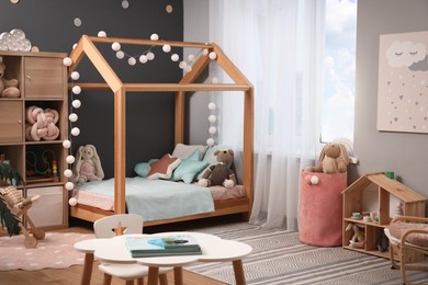 Photo of Comfortable house bed in child room. Stylish interior