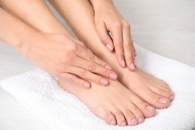 Woman touching her smooth feet on white towel, closeup. Spa treatment