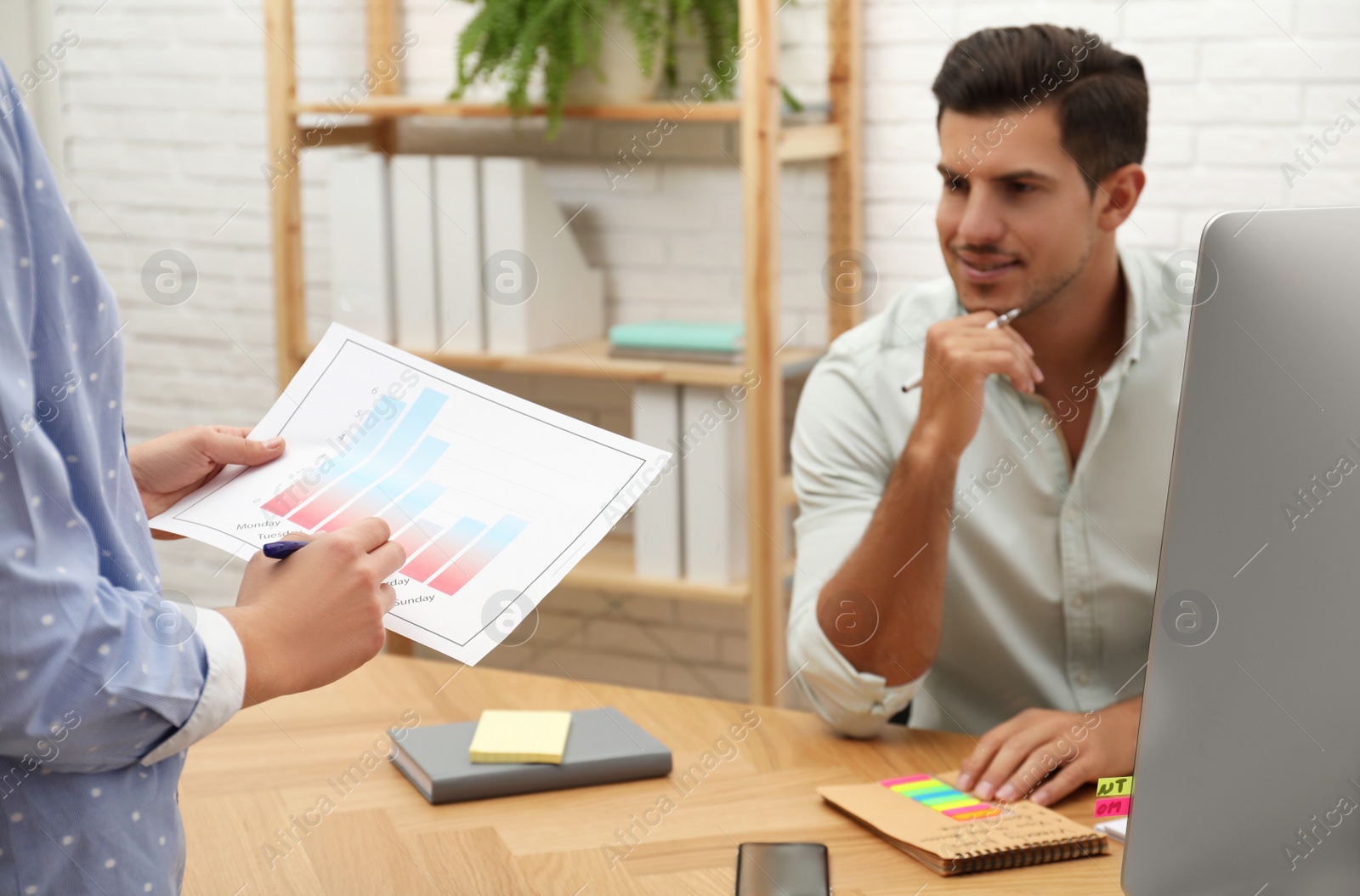 Photo of Colleagues making schedule using calendar in office