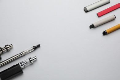 Photo of Many electronic smoking devices on white background, flat lay. Space for text