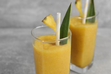 Photo of Tasty pineapple smoothie on light gray table, closeup