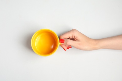 Woman with empty cup on light background, top view