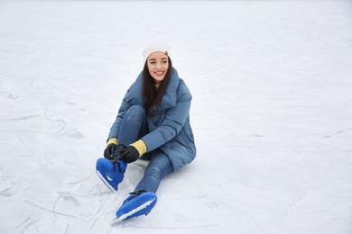 Photo of Woman adjusting figure skate while sitting on ice rink. Space for text