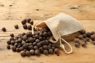 Photo of Aromatic allspice pepper grains and sack on wooden table