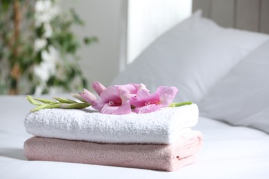 Terry towels with beautiful flower on bed indoors, space for text