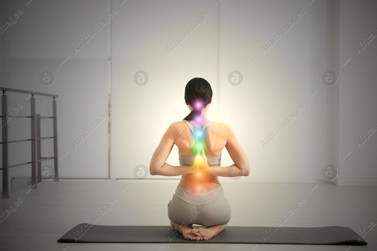 Image of Young woman with chakra points practicing yoga in studio, back view. Healing energy 