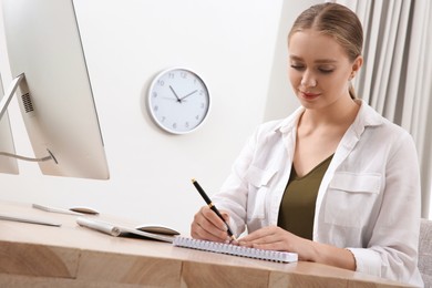 Young woman solving sudoku puzzle at workplace in office