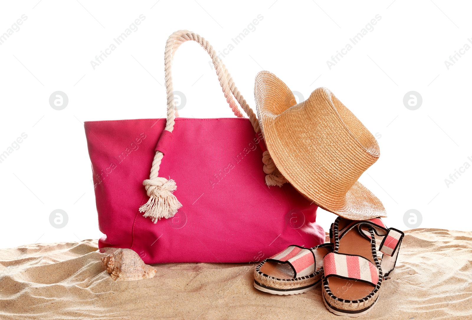 Photo of Stylish coral bag and beach accessories on sand against white background