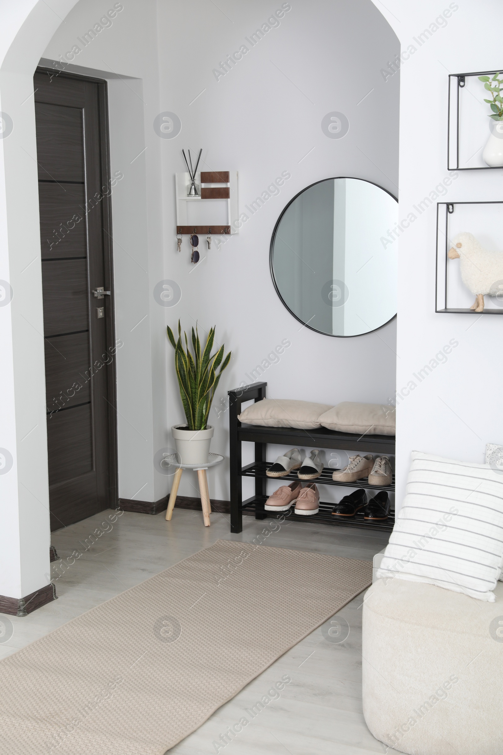 Photo of Hallway interior with stylish furniture and round mirror on light wall