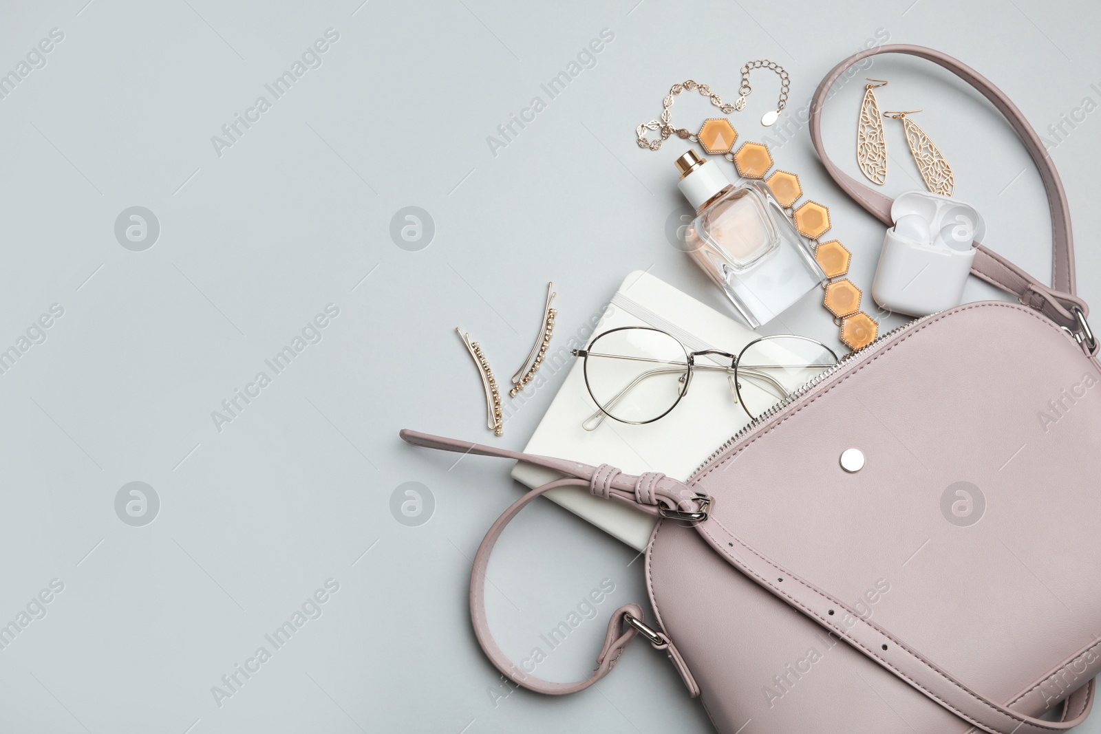 Photo of Stylish woman's bag with accessories on light grey background, flat lay. Space for text